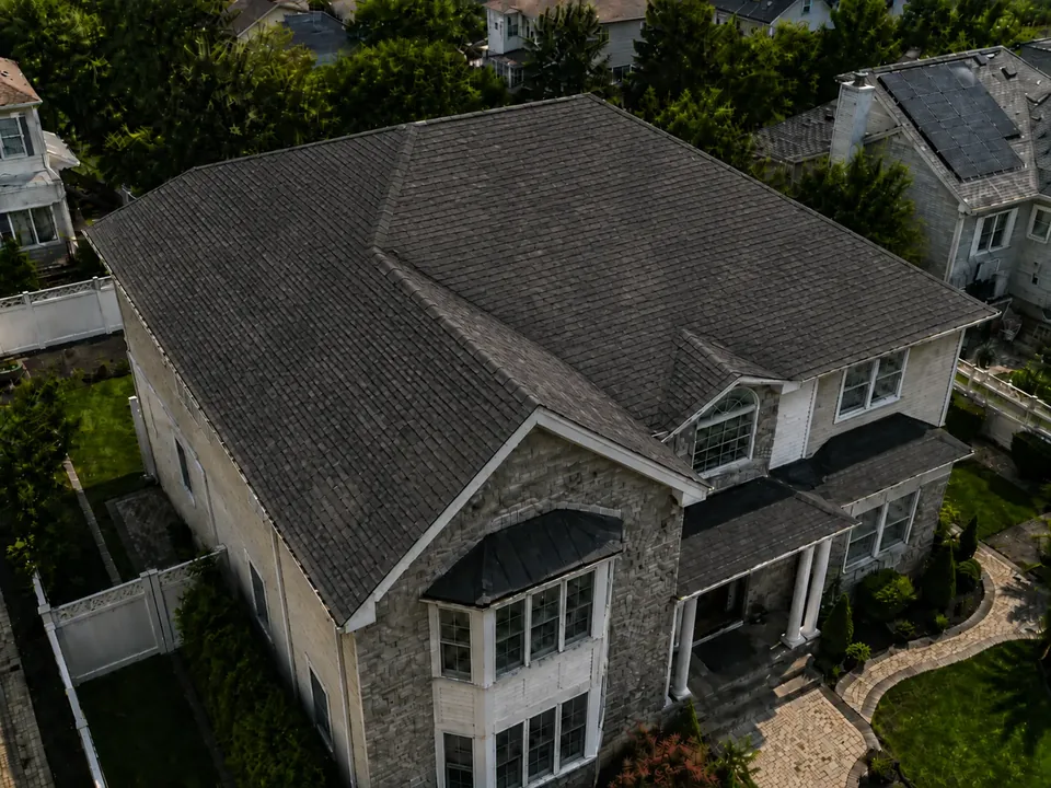 Aerial three-quarter view of the house with its existing aged roof.